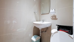 A bathroom with a white sink, a mirror, and a toilet.