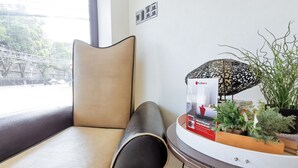 A chair with a high backrest and a cushioned seat, positioned next to a table with a decorative item and a potted plant.