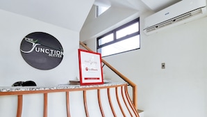 A reception area with a modern design, featuring a reception desk, a framed sign, and a staircase with a wooden railing.