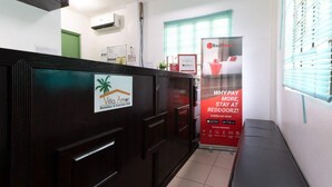 Ein Empfangsbereich mit einem Schild für Vila Amor Restobar & Function Hall, einer RedDoorz-Werbeanzeige und einer Bank.