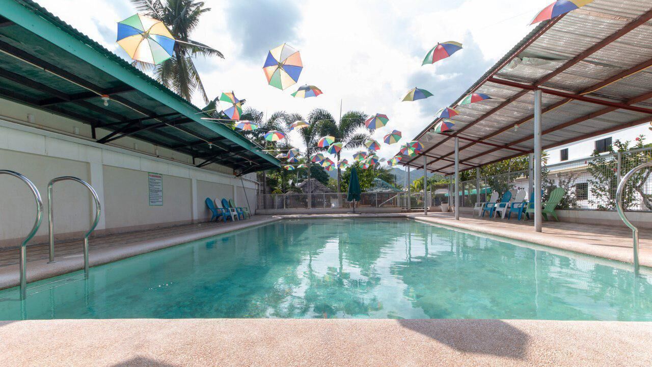 A swimming pool with a covered area and multiple colorful umbrellas.