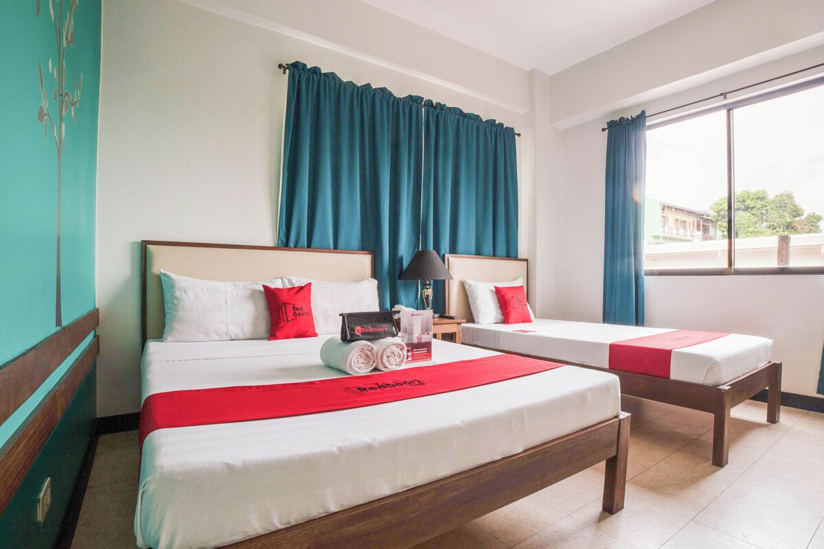 Una habitación de hotel con dos camas, una ventana con cortinas y vistas al exterior.