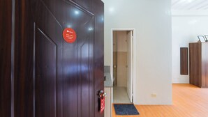 A wooden door with a red sign, a bathroom with a white sink and mirror, and a wooden floor.