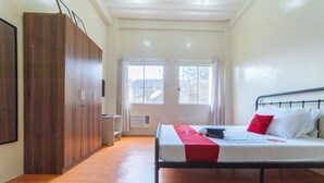 A bedroom with a bed, wooden wardrobe, and a window with curtains.