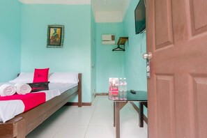 A room with a bed, a table with bottled water, a TV, and a door.