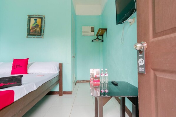 A room with a bed, a table with water bottles, a TV, and a door with a 'Do Not Disturb' sign. - RedDoorz @ Dinagpan Street Coron (Coron)