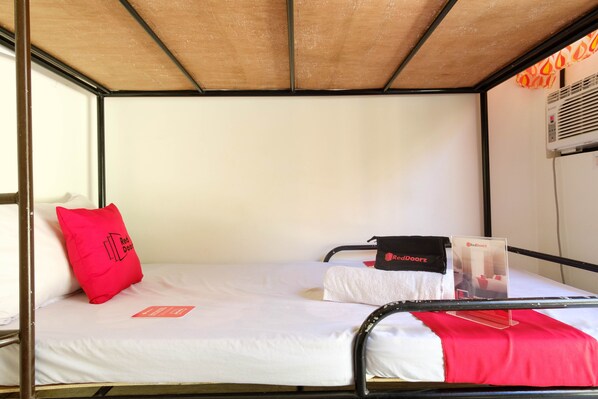 A single bed with a white mattress, a red pillow, and a black bag on the side. - RedDoorz @ Governors Drive Coron (Coron)
