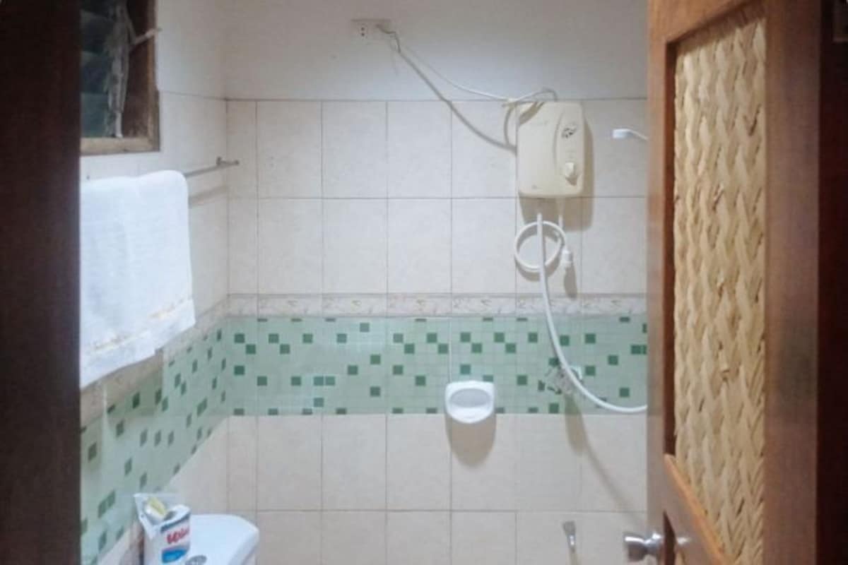 A small bathroom with a toilet, a hand dryer, and a wall-mounted electrical outlet.