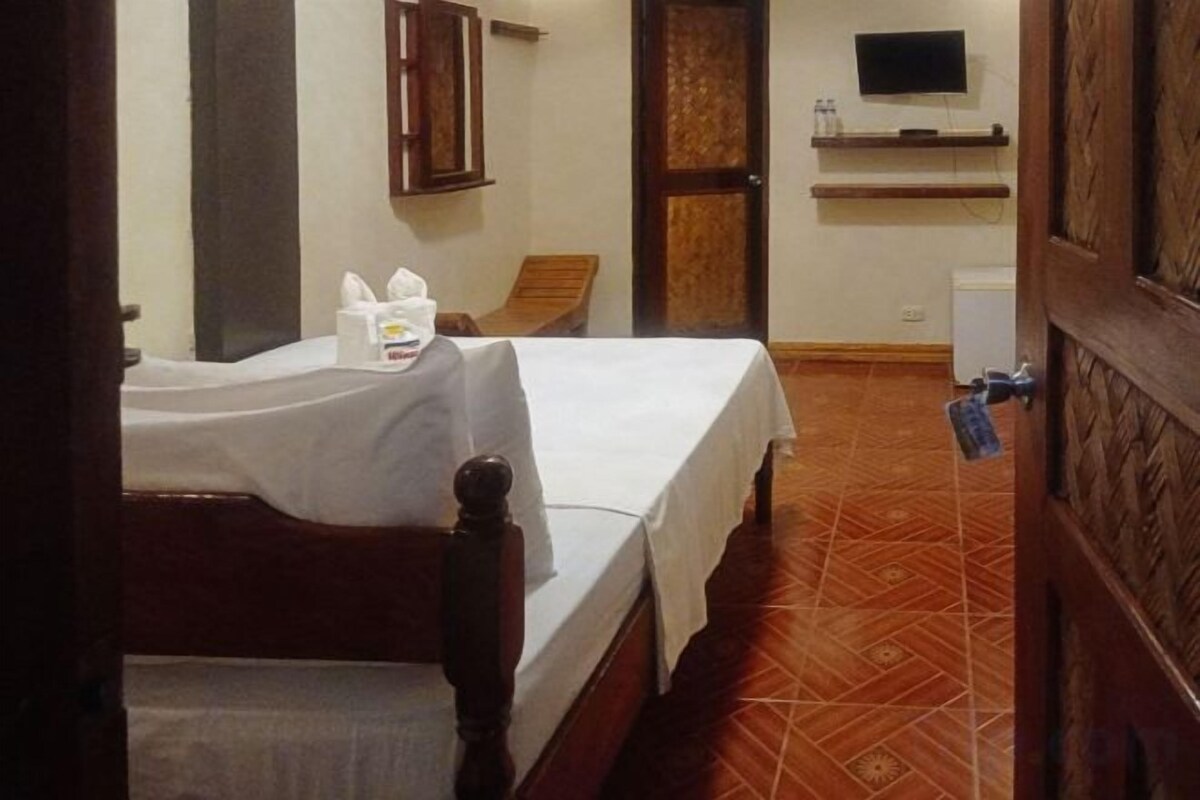 A hotel room with two beds, a television, a cabinet, and a tiled floor.