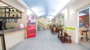 A hotel lobby with a reception desk, a large RedDoorz sign, and a staircase leading to the upper floor. - RedDoorz @ Praferosa Resort Hotel Calamba (Calamba)