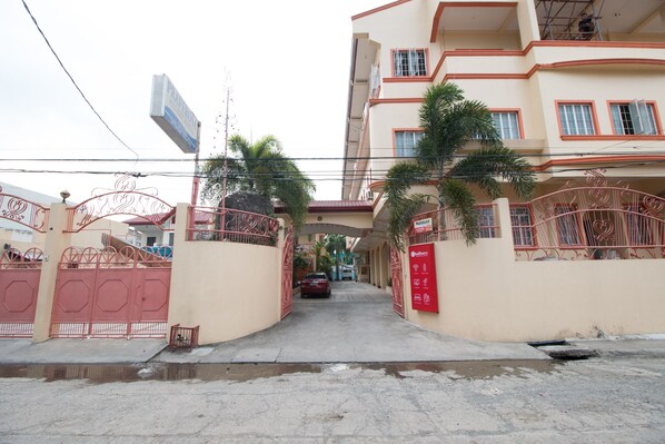 A multi-story residential building with a gated entrance, palm trees, and a visible signboard. - RedDoorz @ Praferosa Resort Hotel Calamba (Calamba)