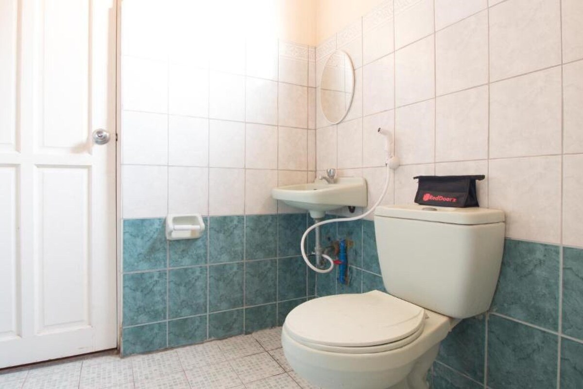 A bathroom with a toilet, sink, and a mirror.