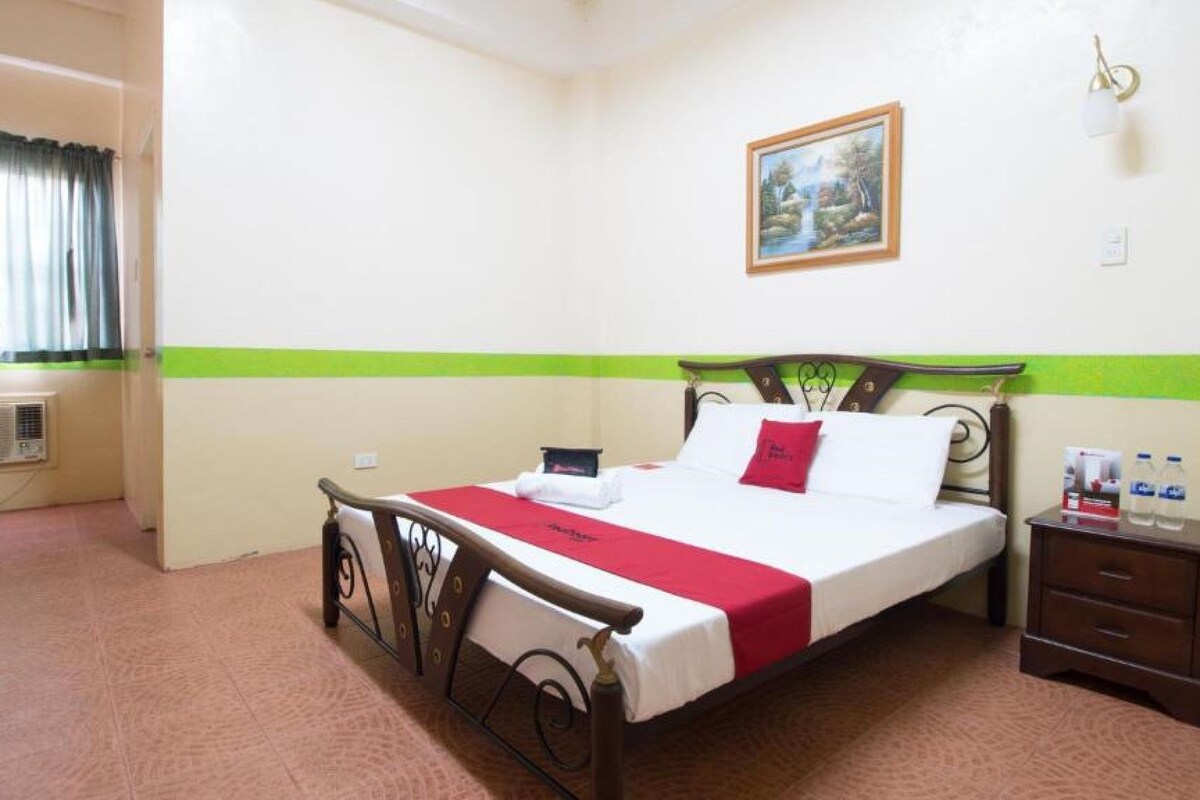 Quarto de hotel com cama, mesa de cabeceira e um quadro na parede.