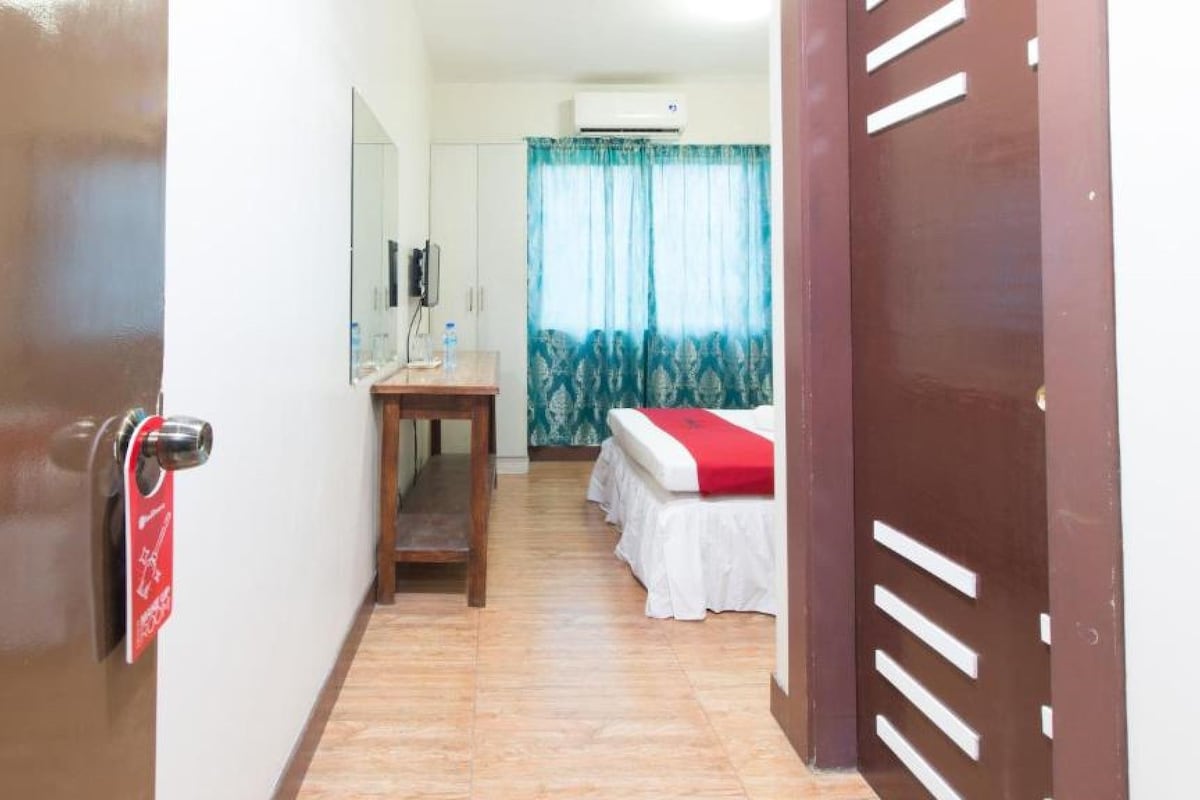 Une chambre d’hôtel équipée d’un lit, d’un bureau, d’un miroir et d’un appareil de climatisation.
