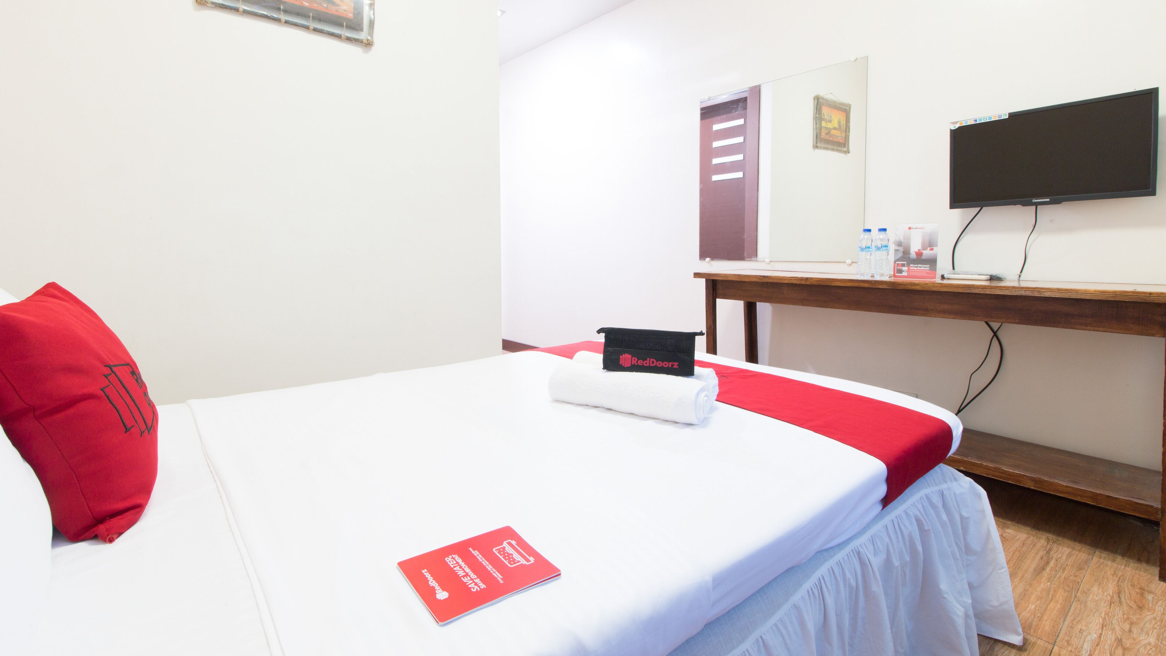 Une chambre d’hôtel avec un lit, un bureau, une télévision et une porte.