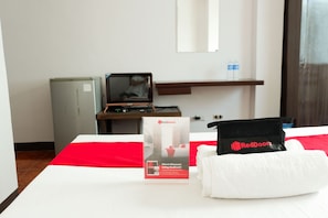 Une chambre d’hôtel équipée d’un lit, d’un article promotionnel RedDoorz, d’un réfrigérateur et d’une télévision.