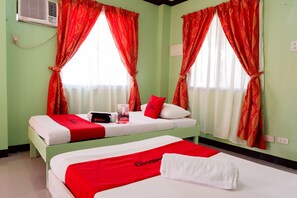 A hotel room with two beds, red and white bedding, a red and white pillow, a red blanket, and a red and white towel. - RedDoorz near Maribago Barangay Hall (Lapu-Lapu)