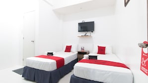 A hotel room with two beds, each with a red and white bedspread, a flat-screen TV mounted on the wall, and a small wooden nightstand between the beds. - RedDoorz near Liceo De Cagayan University Highschool (Cagayan de Oro)