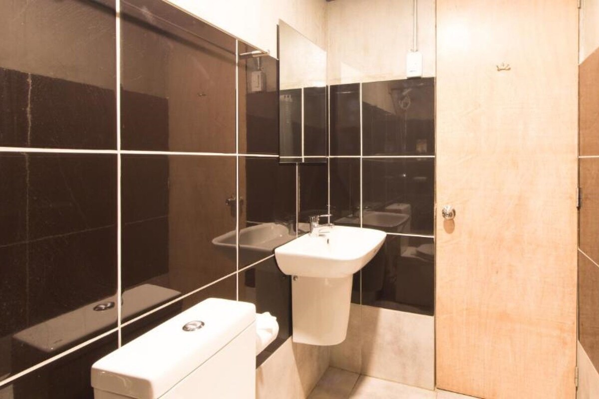 Un baño moderno con un espejo grande, un lavamanos y un inodoro.