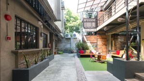 A narrow outdoor corridor with a green artificial turf area, seating with cushions, and potted plants. - RedDoorz Plus @ Taft North Mandurriao (Iloilo)