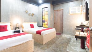 A hotel room with two beds, a wooden door, a window with a colorful view, and a desk with a computer. - RedDoorz Plus @ Taft North Mandurriao (Iloilo)
