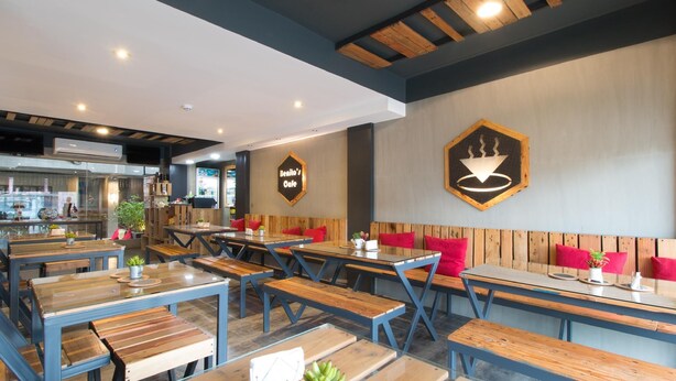 A cafe with wooden tables and benches, a visible menu board, and a logo on the wall. - RedDoorz Plus @ Taft North Mandurriao (Iloilo)