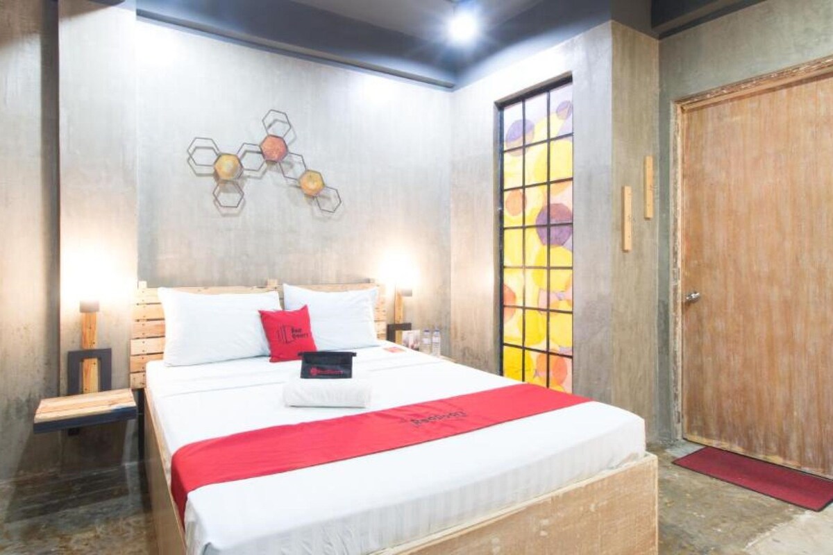 Una camera d'albergo con un letto, comodini, un'armadio in legno e una parete con decorazioni geometriche.
