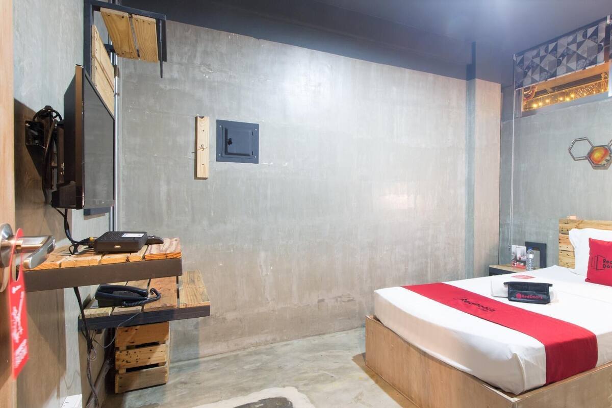 Un dormitorio con una cama, un escritorio, una silla, un televisor y una estantería en la pared.