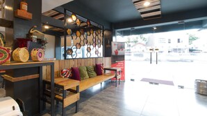 A modern interior with a wooden bench, a wall-mounted display of woven baskets, and a glass door leading outside. - RedDoorz Plus @ Taft North Mandurriao (Iloilo)