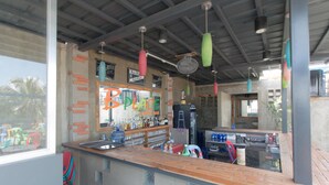 A bar with a rustic interior, featuring a wooden counter, hanging lights, and a visible sign that reads "BPLACE SUNSET BAR". - RedDoorz Plus @ Taft North Mandurriao (Iloilo)