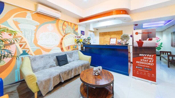 Un área de recepción con un sofá, una mesa de madera y un mural colorido en la pared.
