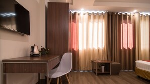 A hotel room with a wooden desk, a chair, a bed, a TV mounted on the wall, and a window with curtains. - RedDoorz near Giap Bat (Hanoi)