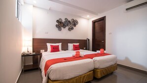 A hotel room with a double bed, a bedside table with a lamp, a wall art piece, and a wooden door. - RedDoorz near Giap Bat (Hanoi)
