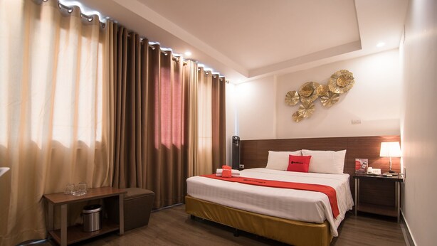 A hotel room with a bed, bedside table, lamp, and curtains. - RedDoorz near Giap Bat (Hanoi)