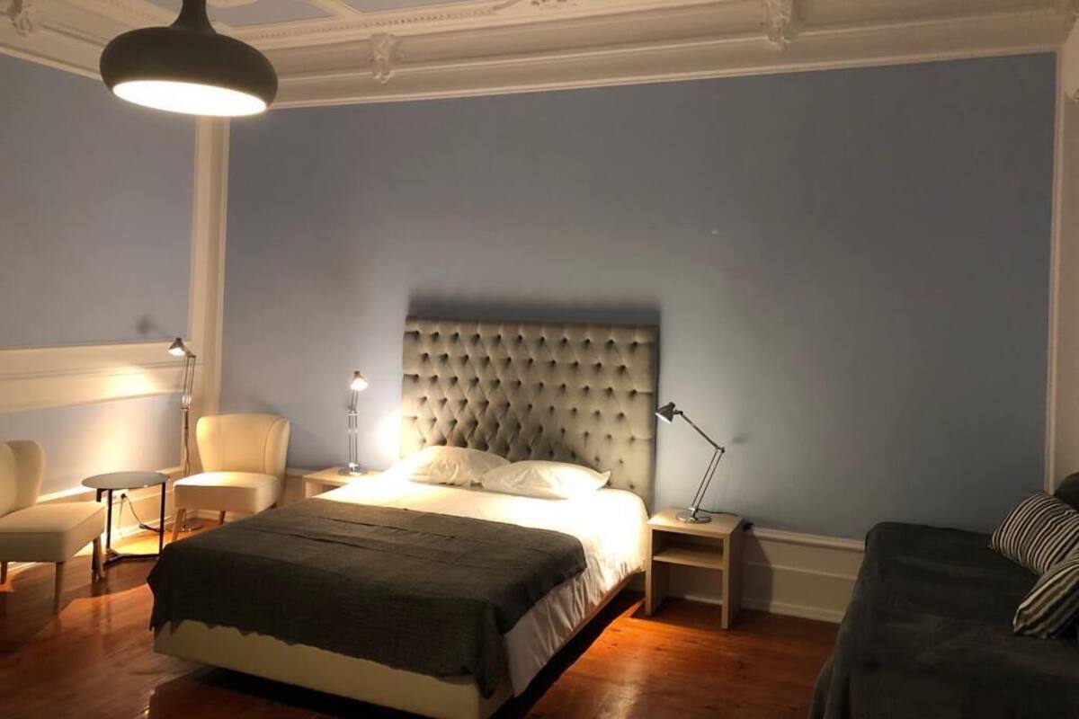 Ein Schlafzimmer mit einem großen Bett, einem Sessel, einem Nachttisch, einer Lampe und einem Schlafsofa.