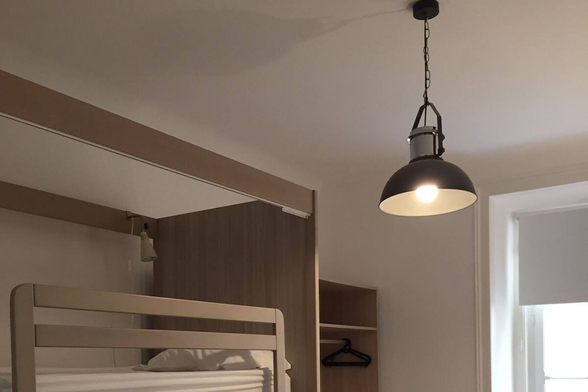 Ein Schlafraum mit Etagenbetten, einer Hängeleuchte, einem Holzschrank und einem Schreibtisch mit Stuhl.