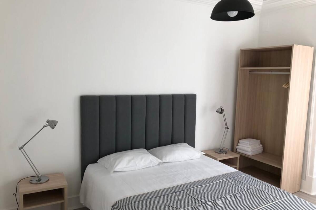 Ein Schlafzimmer mit einem Bett, Nachttischen, einem Kleiderschrank und einer Pendelleuchte.