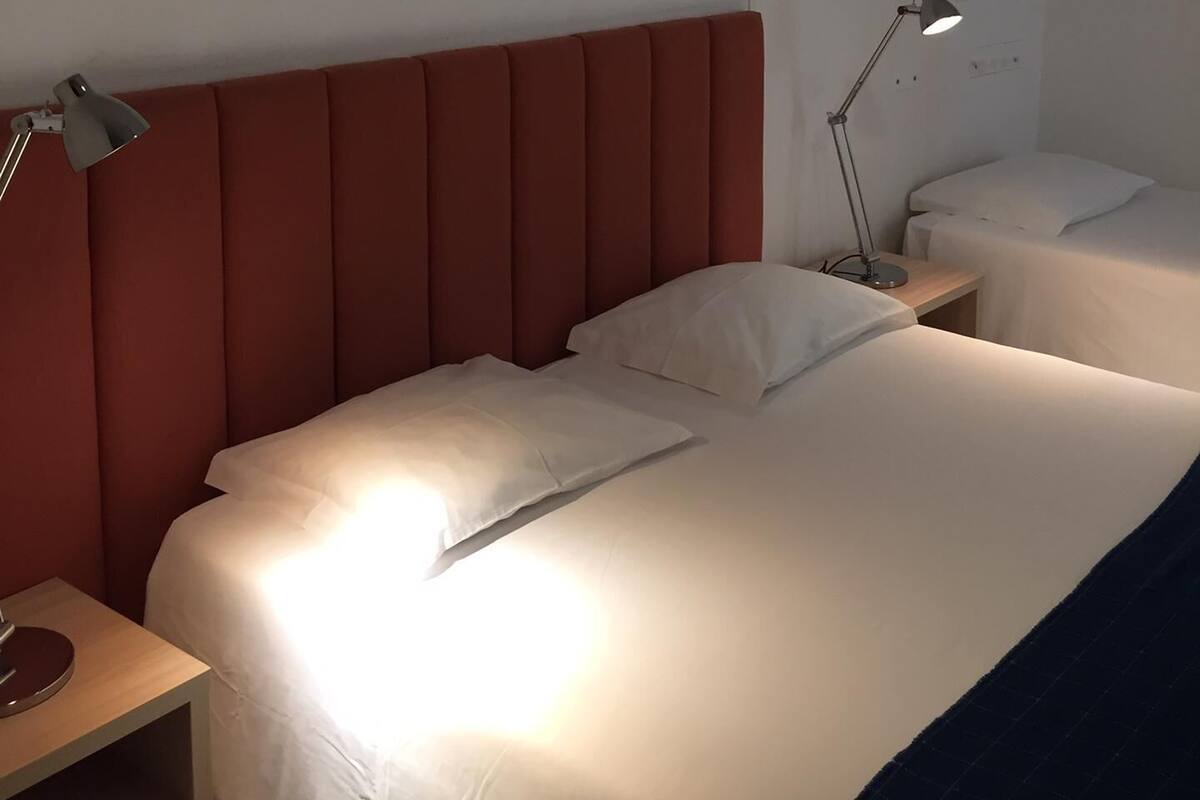 Ein Hotelzimmer mit einem großen Bett, zwei Nachttischen und zwei Lampen.
