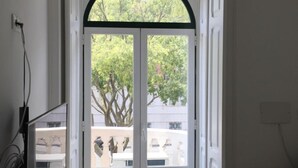A room with a large arched doorway, a bench, a table with books, and a small sofa. - Be Lisbon Residence Marquês (Lisbon)