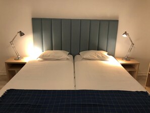 A double bed with a blue headboard, two bedside tables with lamps, and a dark blue blanket. - Be Lisbon Residence Marquês (Lisbon)