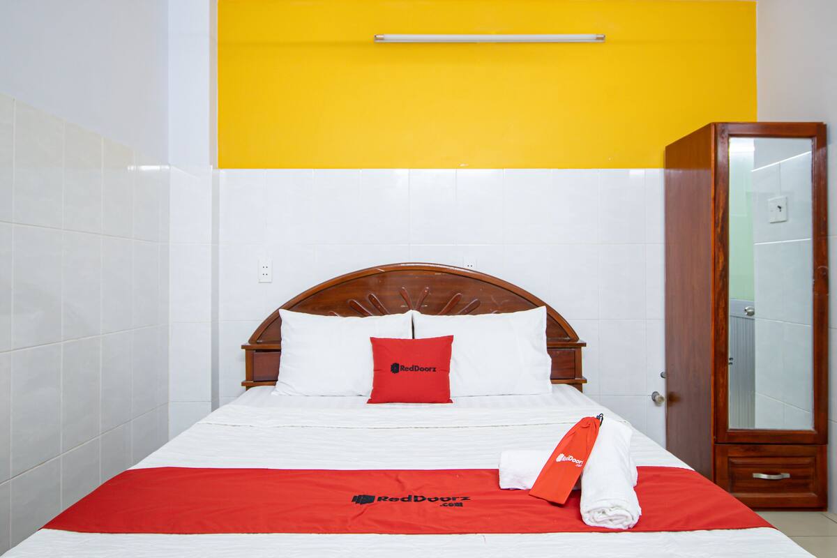A hotel room with a bed, a wardrobe, and a mirror.