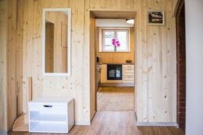 A wooden interior with a kitchen area, a white cabinet, and a window with flowers. - Apartments Arh (Bohinj)