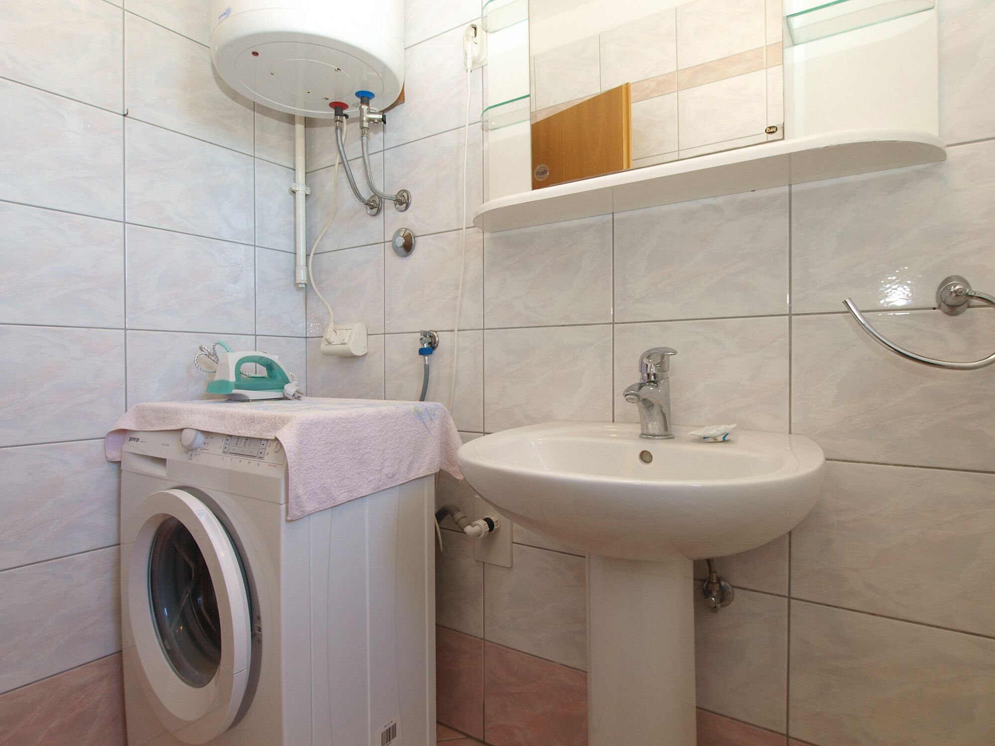Un bagno compatto con lavatrice, lavandino e doccia.