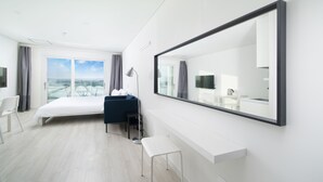 A modern hotel room with a large bed, a desk, a chair, and a large mirror. - Soo Village (Seogwipo)
