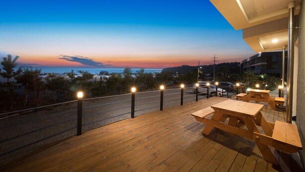 A wooden deck with picnic tables overlooking a sunset view. - Soo Village (Seogwipo)
