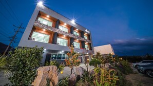 A modern building with multiple floors, large windows, and a well-lit facade. - Soo Village (Seogwipo)