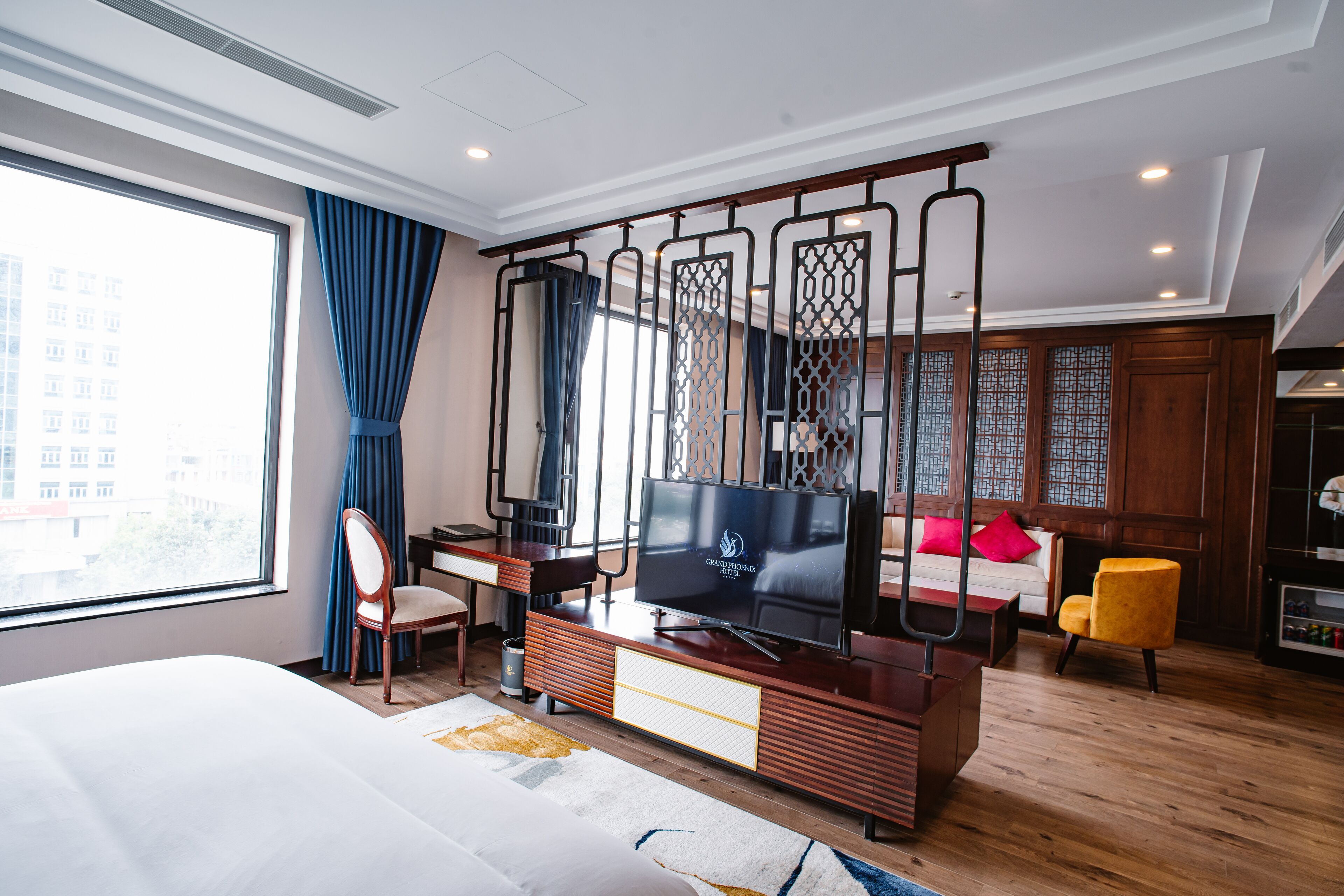 Una habitación de hotel moderna con una cama grande, un escritorio con televisor, un sofá y una silla.
