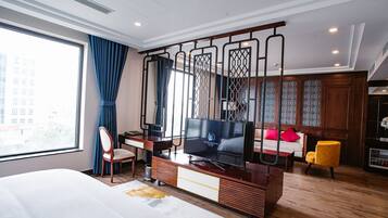 Una habitación de hotel moderna con una cama grande, un escritorio con televisor, un sofá y una silla.