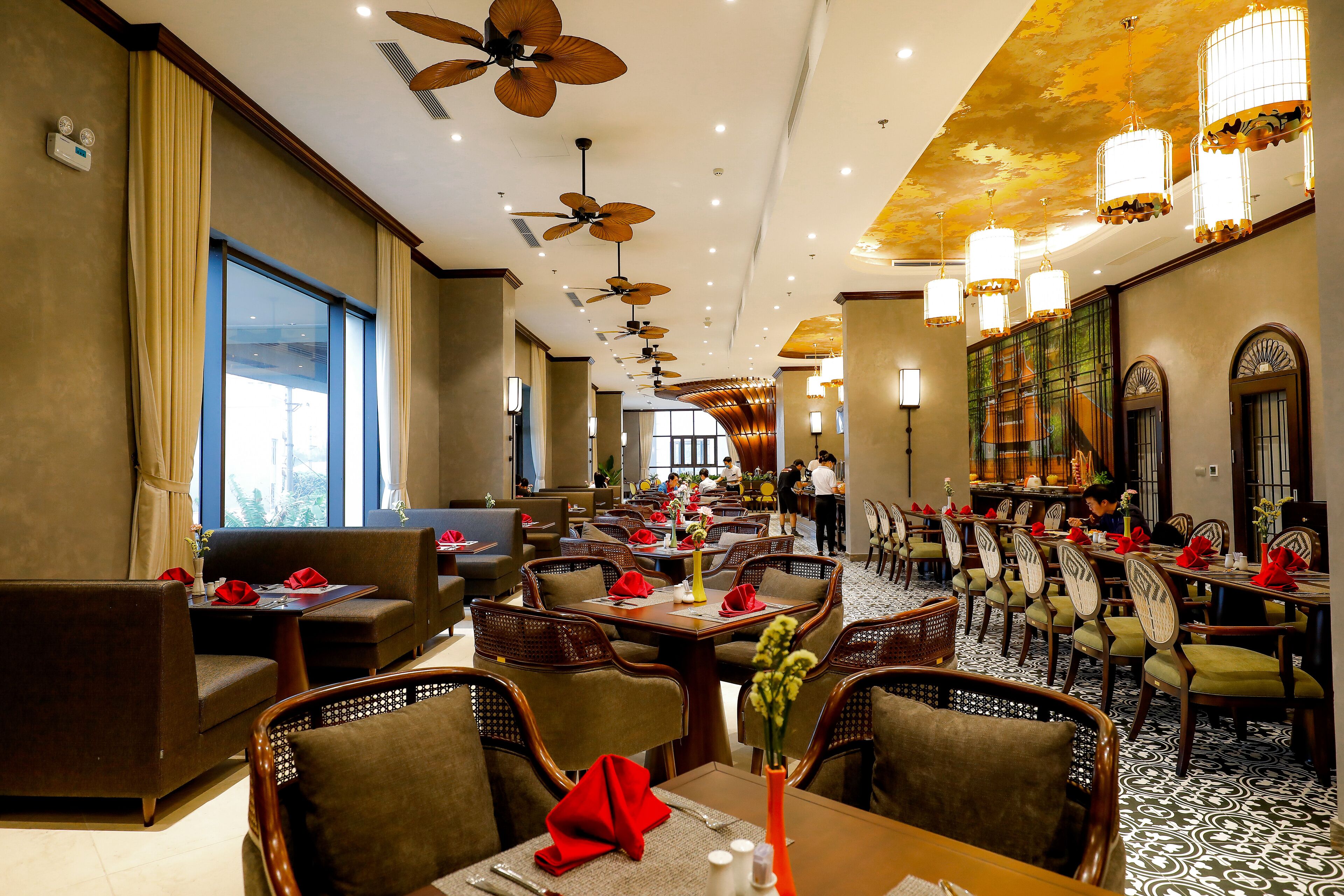 A spacious restaurant with high ceilings, ceiling fans, and a mix of dining tables and booths.