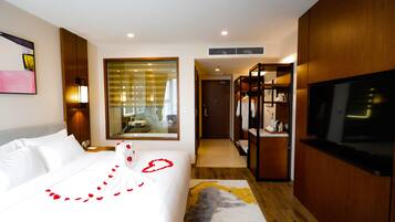 Una habitación de hotel con una cama grande, televisión, armario y espejo.